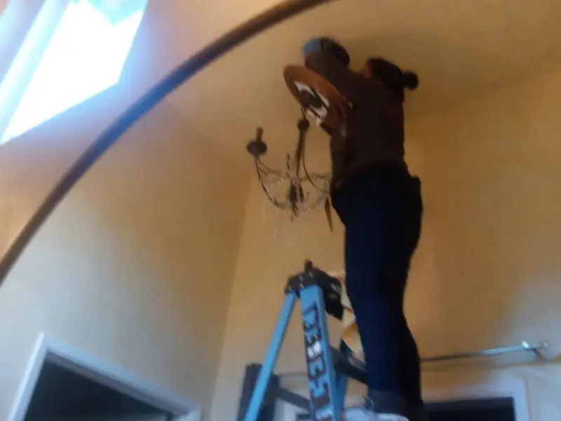 Electrician installing a chandelier in a Rochester residence